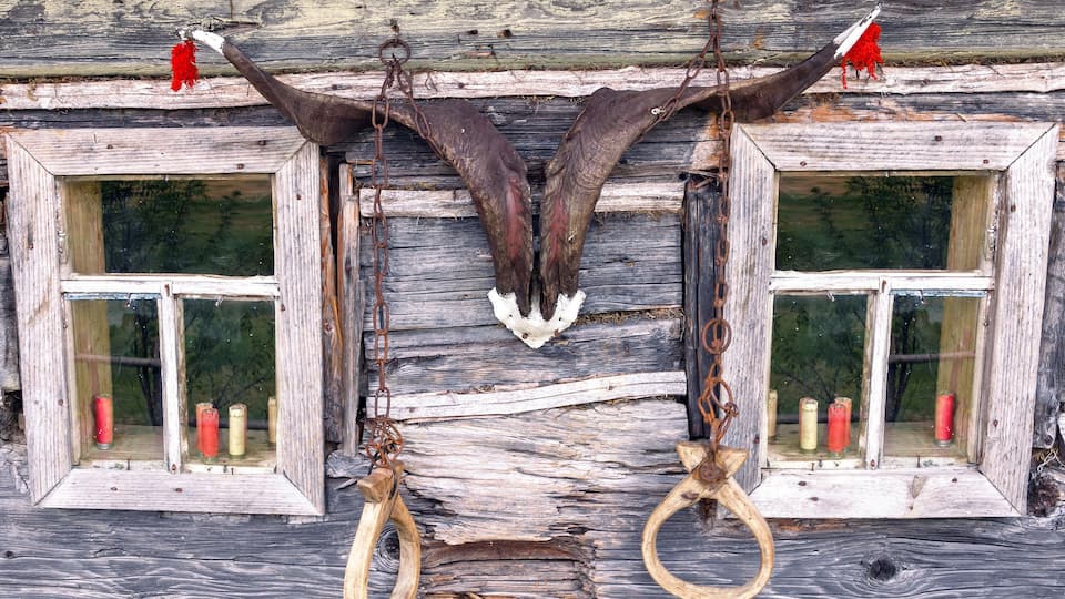 A rustic wooden structure with two windows, each containing a pair of handcuffs hanging from the center.