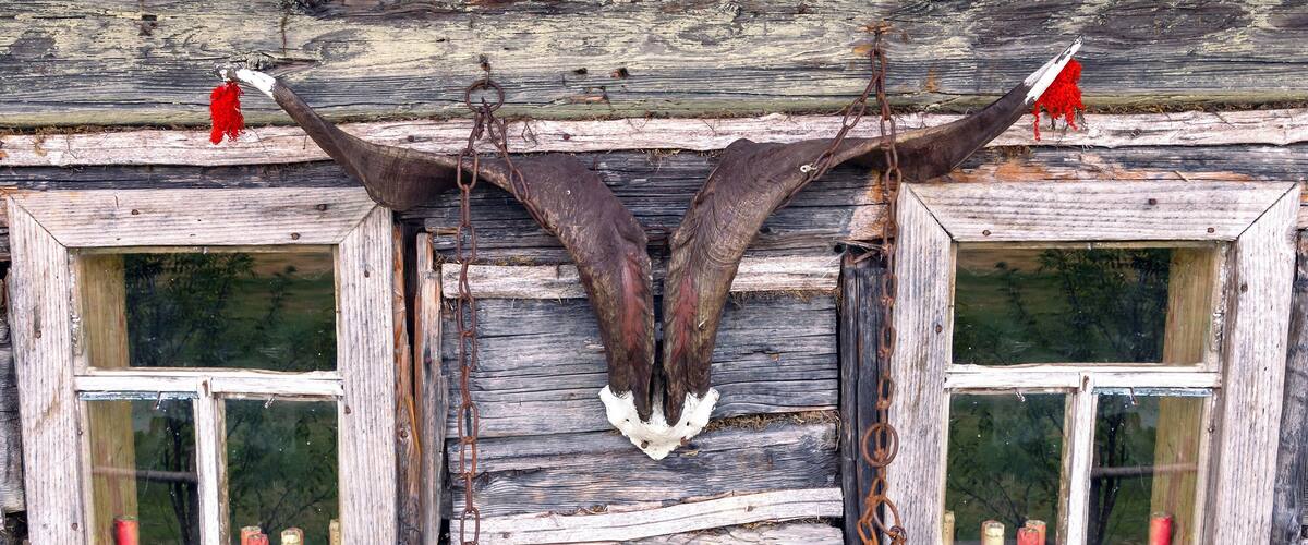A rustic wooden structure with two windows, each containing a pair of handcuffs hanging from the center.