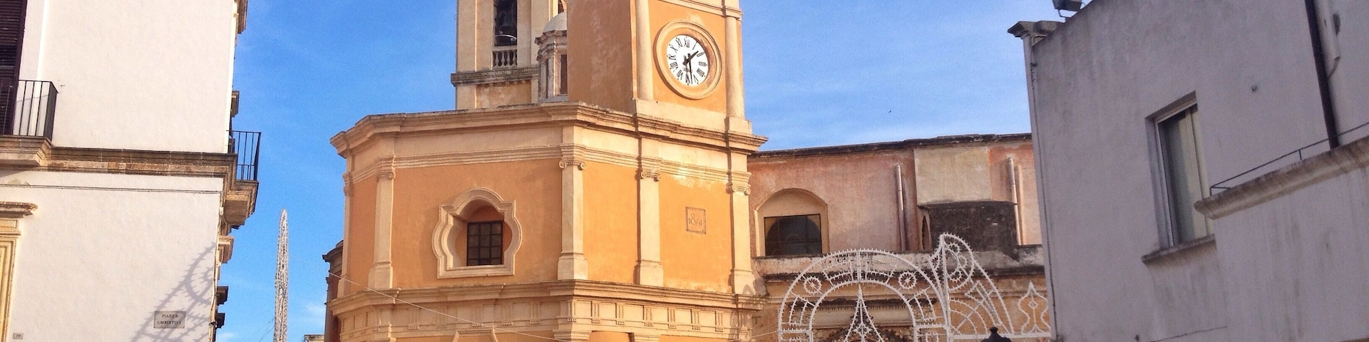 Uma igreja histórica com uma torre do relógio e um arco decorativo.