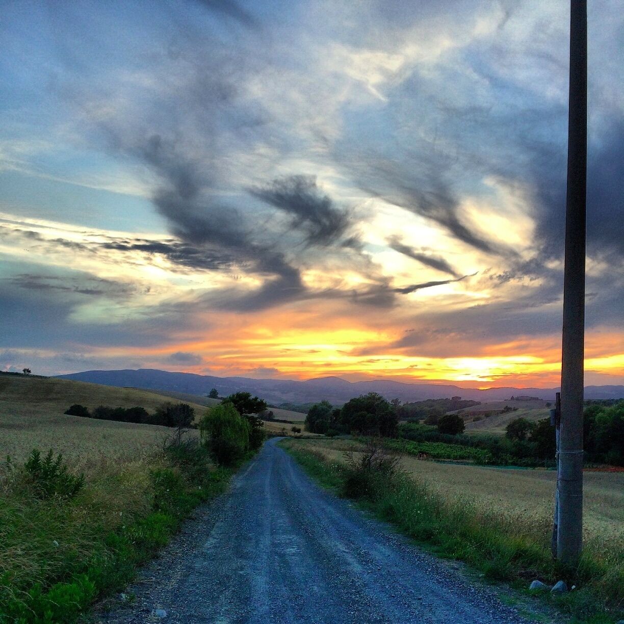 A rural road with a sunset in the distance.