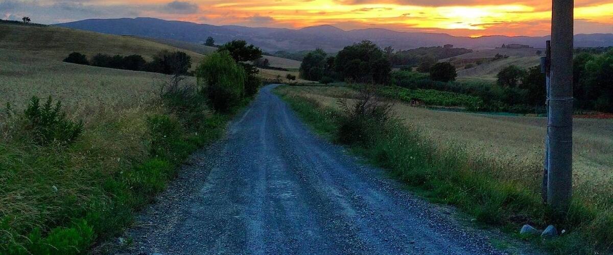 A rural road with a sunset in the distance.