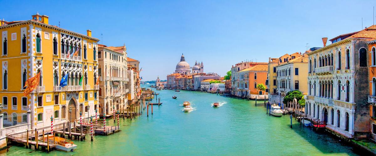 A canal with boats, historic buildings, and a prominent dome in Venice.