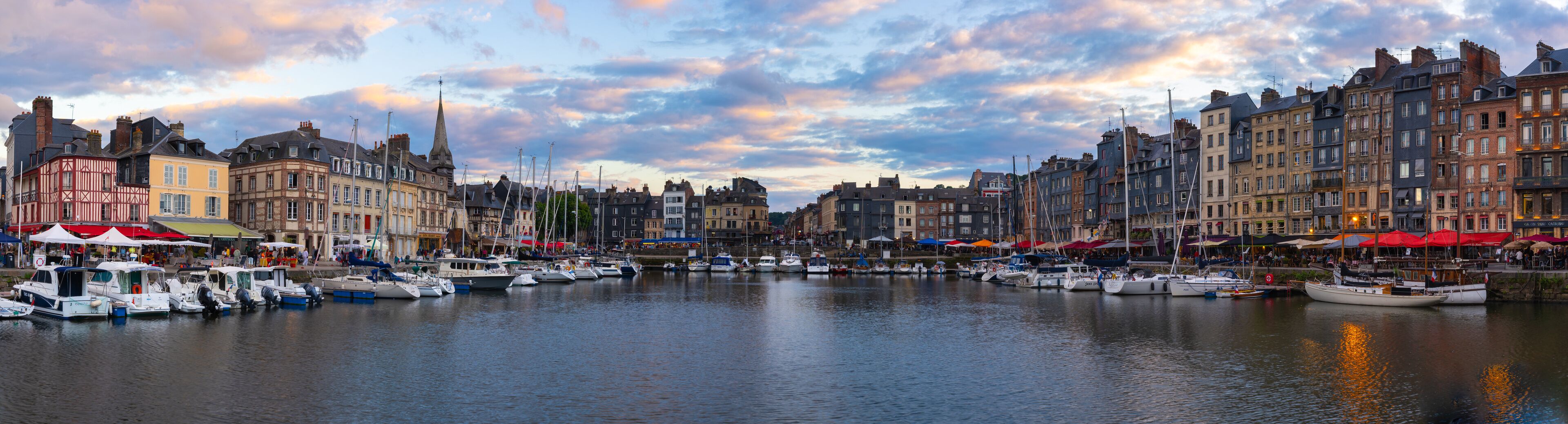 A harbor with boats docked, historic buildings, and a cloudy sky.