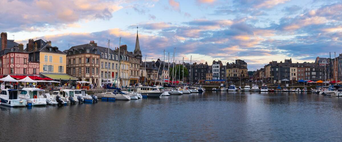 A harbor with boats docked, historic buildings, and a cloudy sky.