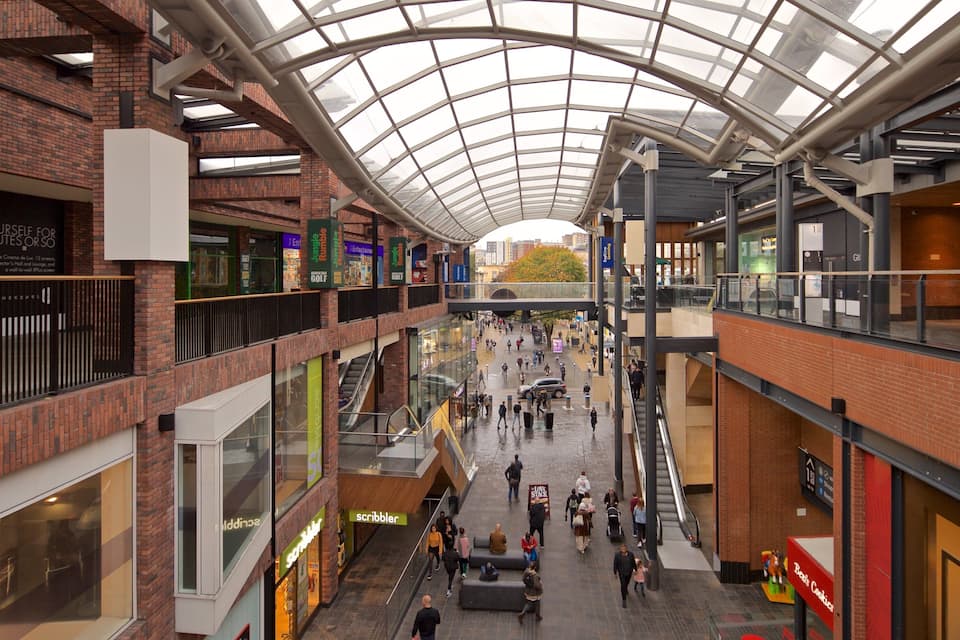 Een meerlaags winkelcentrum met glazen dak, diverse winkels en een centrale doorgang.