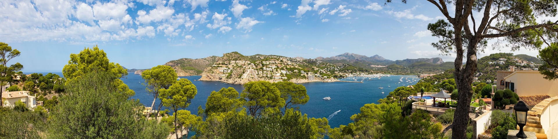 A coastal town with a view of the sea, mountains, and trees.