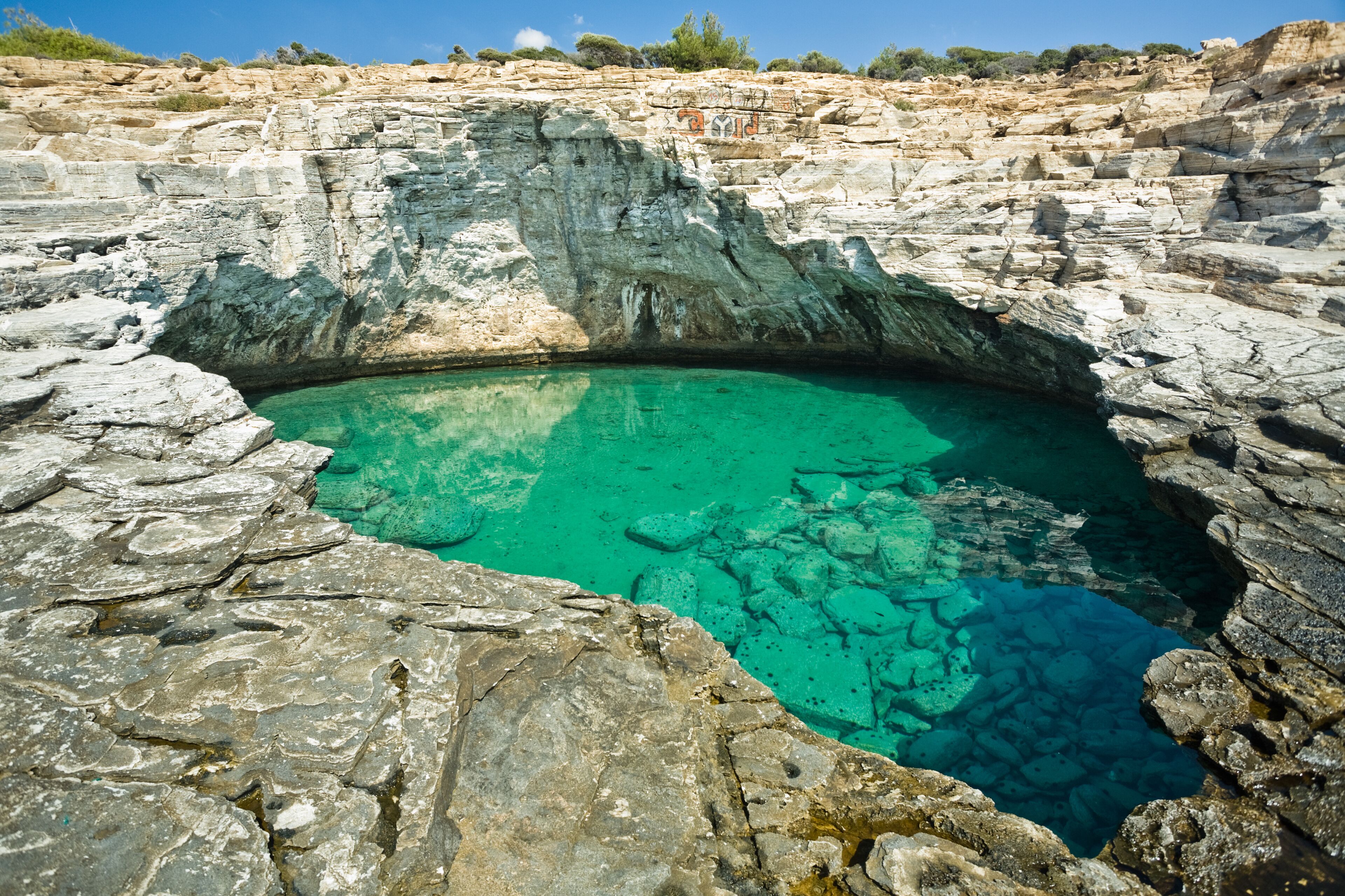 A natural pool surrounded by rocky cliffs.