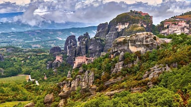 Paisagem montanhosa com formações rochosas imponentes e uma vista distante de um vale.