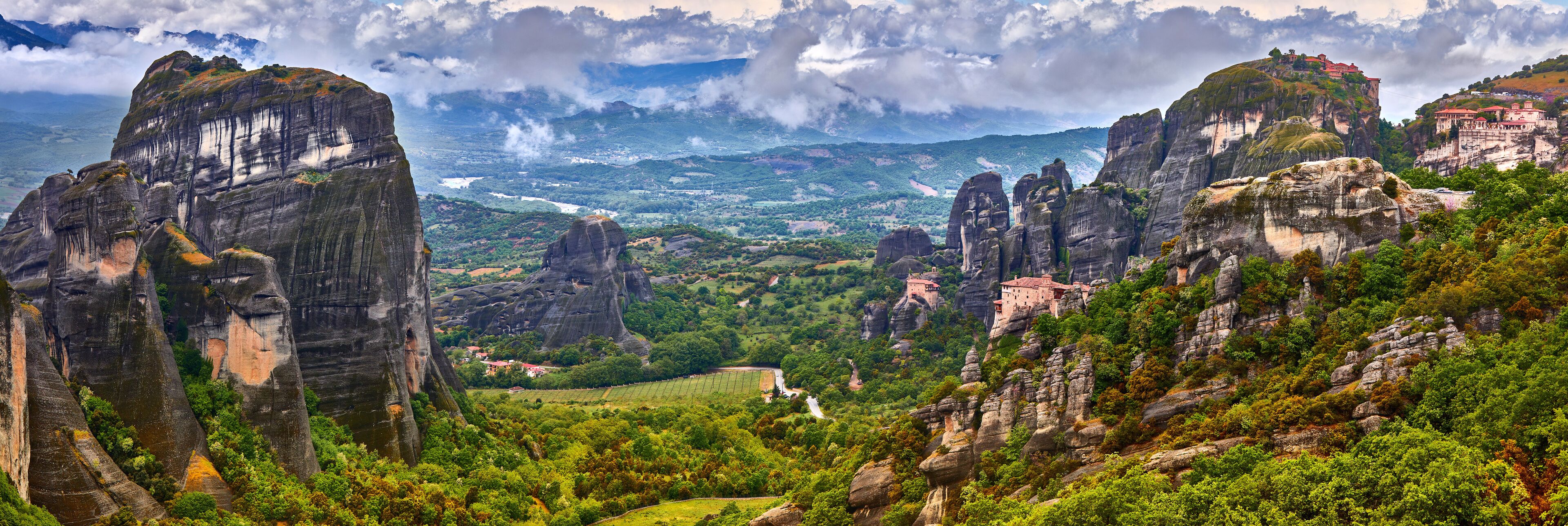 A mountainous landscape with prominent rock formations and a distant view of a valley.