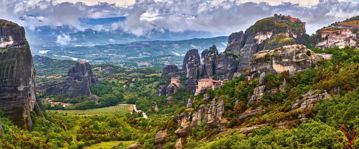 A mountainous landscape with prominent rock formations and a distant view of a valley.