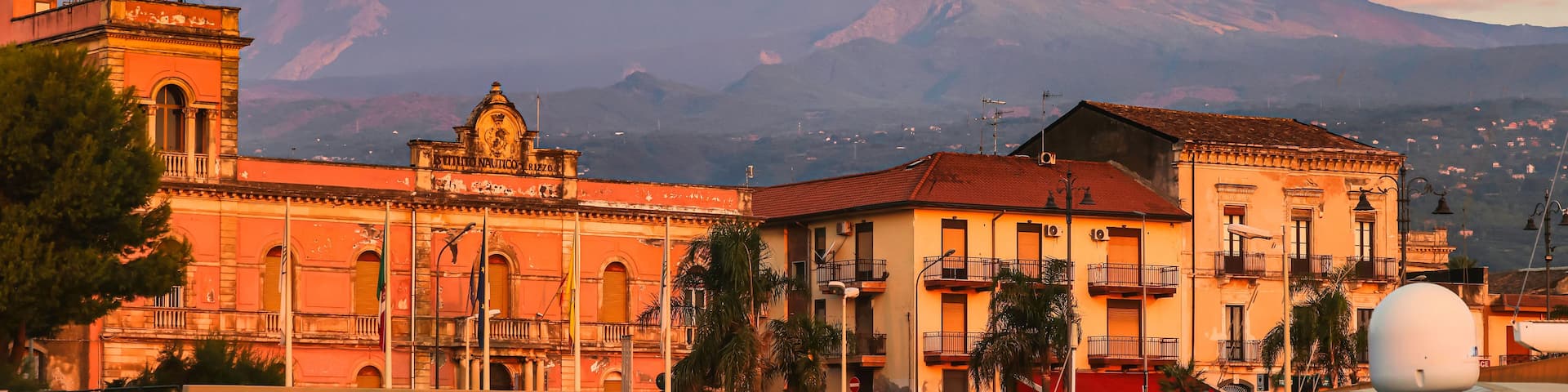 A mountain with a plume of smoke, a historic building with a dome, and a clear sky.