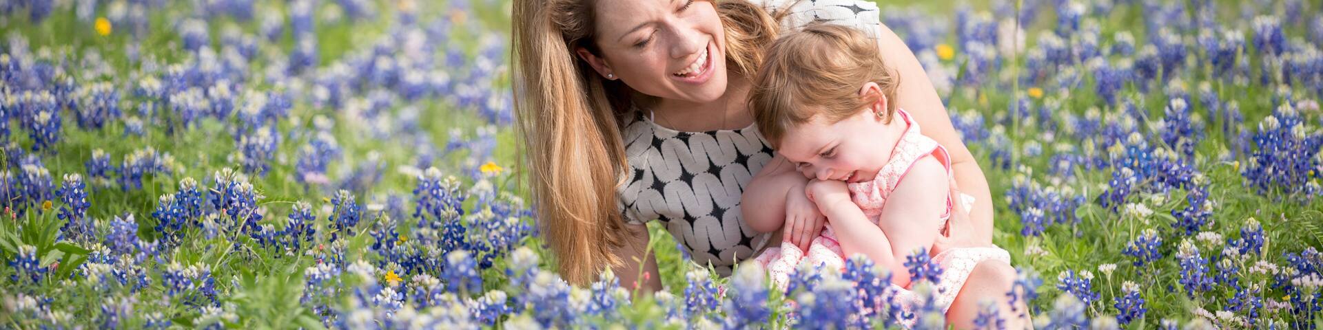 A field of blue flowers with a person and a child.