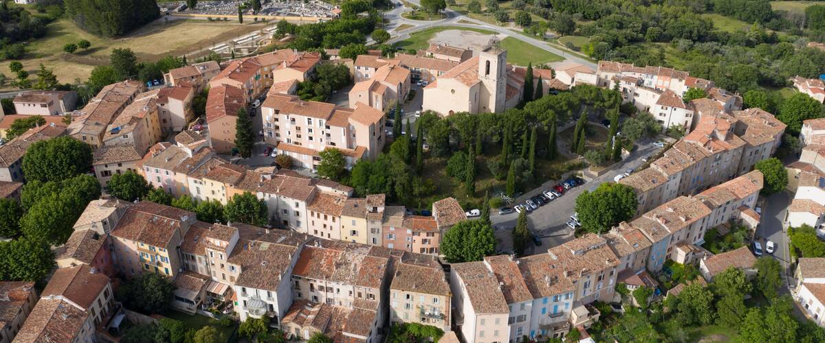 A historic town with a central church, surrounded by terraced buildings and lush greenery.