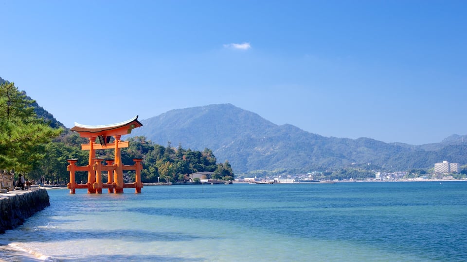 A traditional Japanese torii gate in a body of water with mountains in the background.