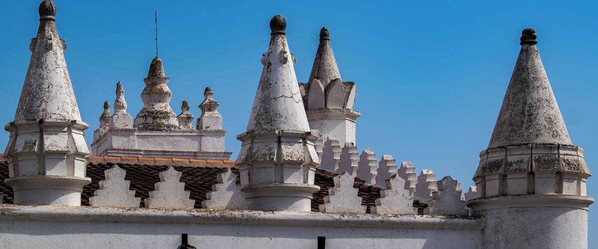 A historic building with multiple pointed towers and a clear blue sky.