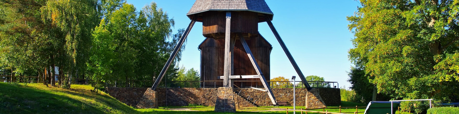 Una torre de madera con techo cónico en un parque cubierto de hierba.