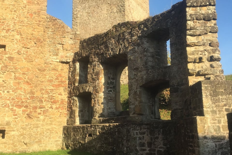 Um castelo de pedra medieval com uma torre alta e janelas em arco.