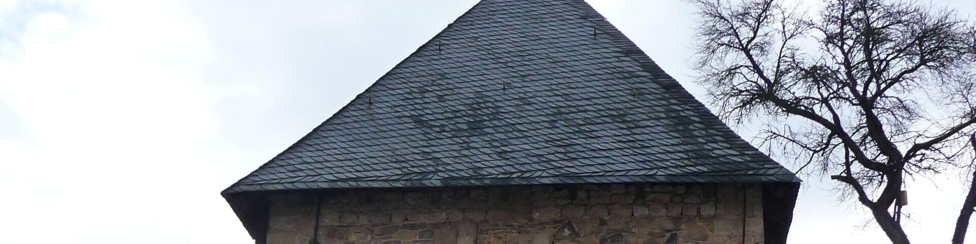 A stone tower with a pointed roof and an arched entrance.