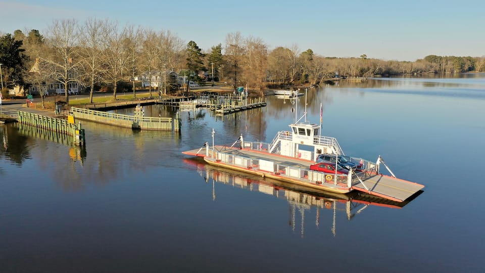 A calm river with a dock and a boat named 'Tina Fallon'.