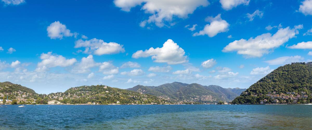 A lake with a town on a hill, boats on the water, and a clear blue sky.