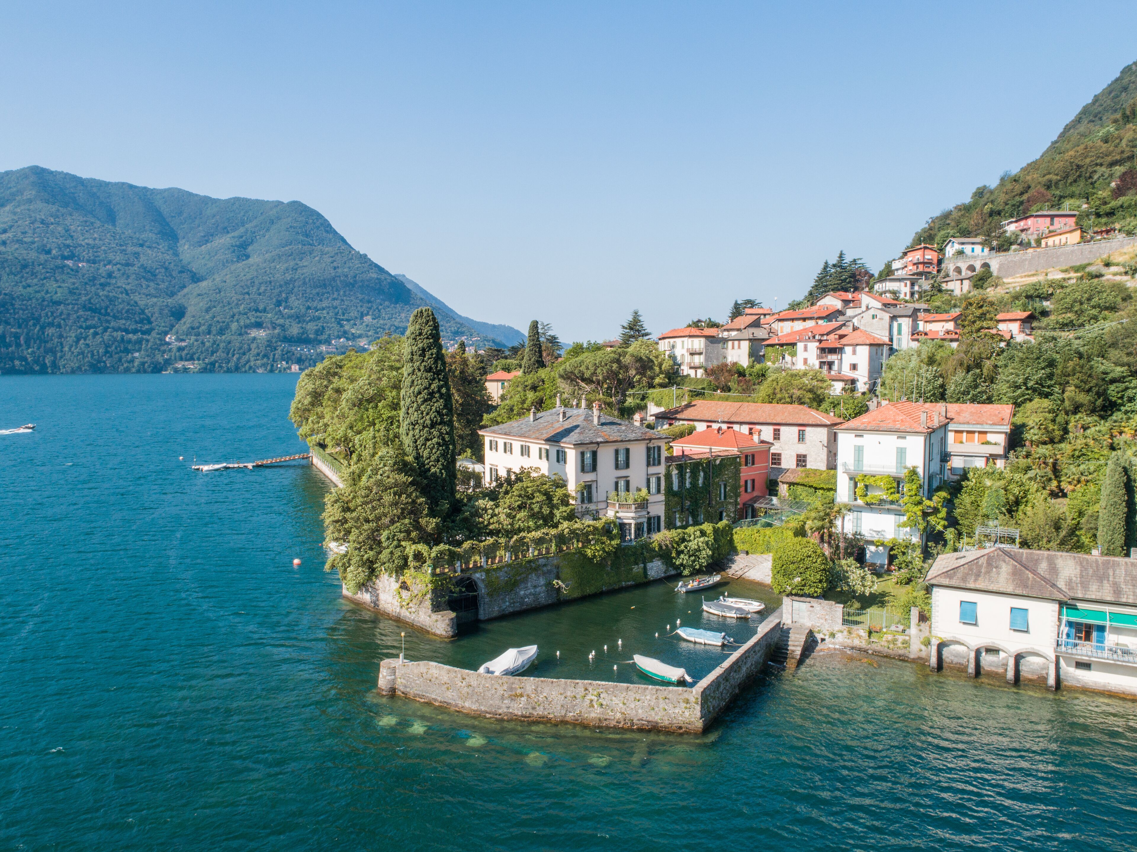 A coastal town with buildings on a hillside overlooking a calm lake.