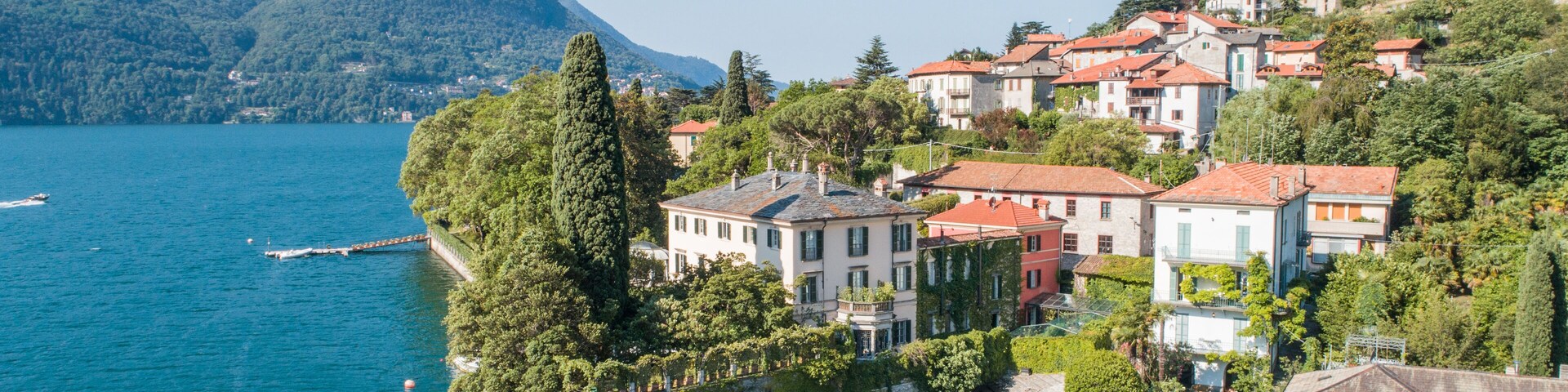 Un pueblo costero con edificios en una colina que domina un lago tranquilo.