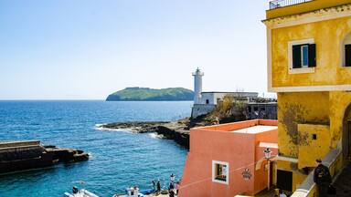 A coastal town with a lighthouse, boats, and colorful buildings.