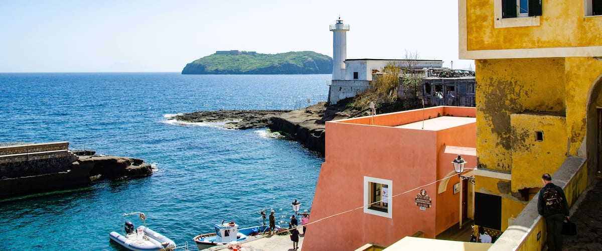 A coastal town with a lighthouse, boats, and colorful buildings.