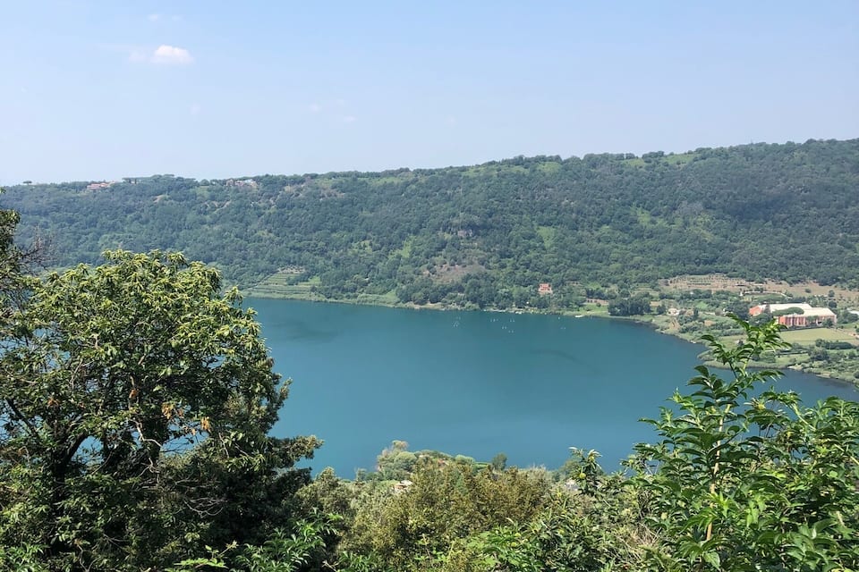 A lake surrounded by dense green forest and hills.