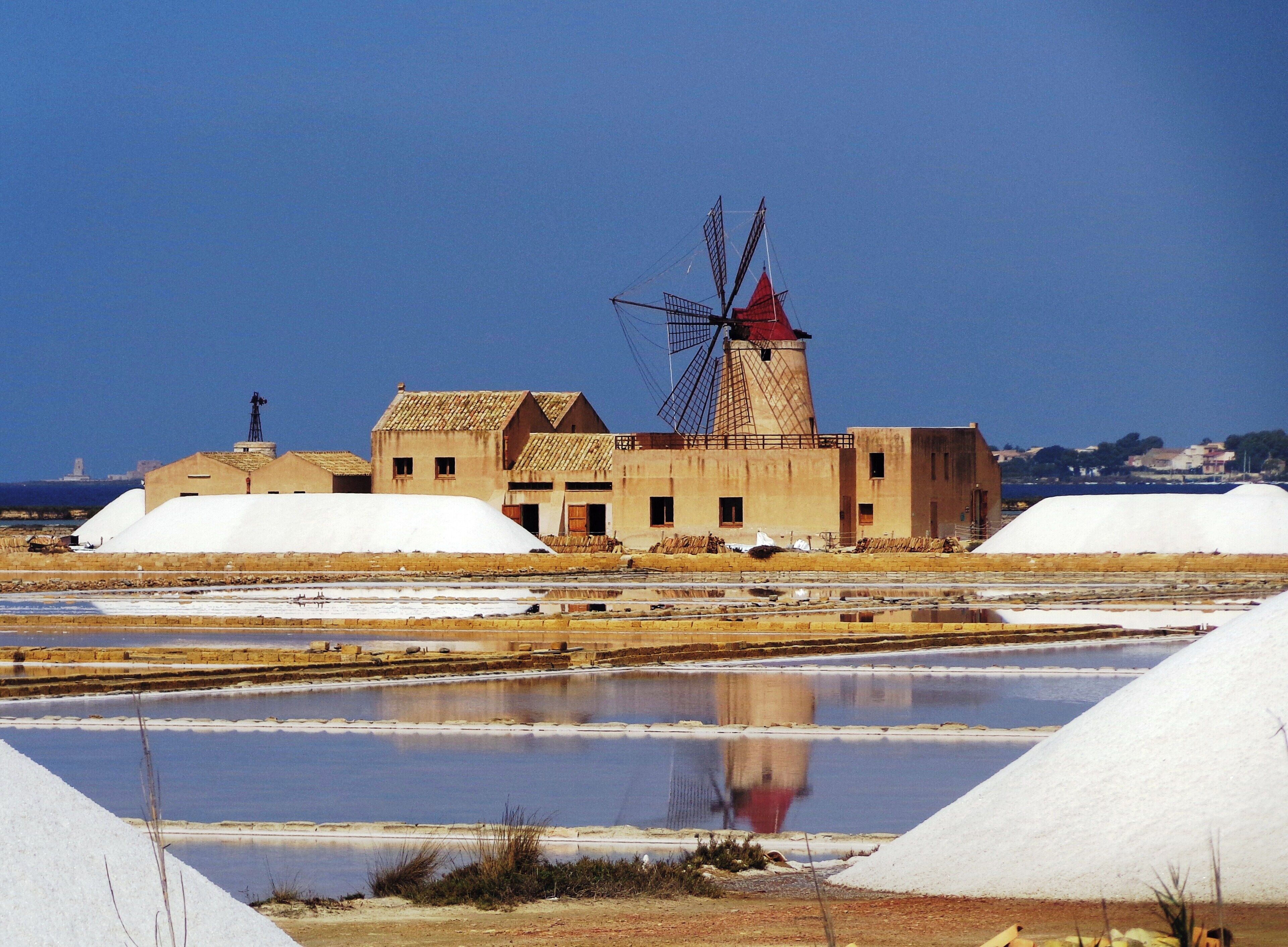 A windmill, salt storage piles, and salt pans.