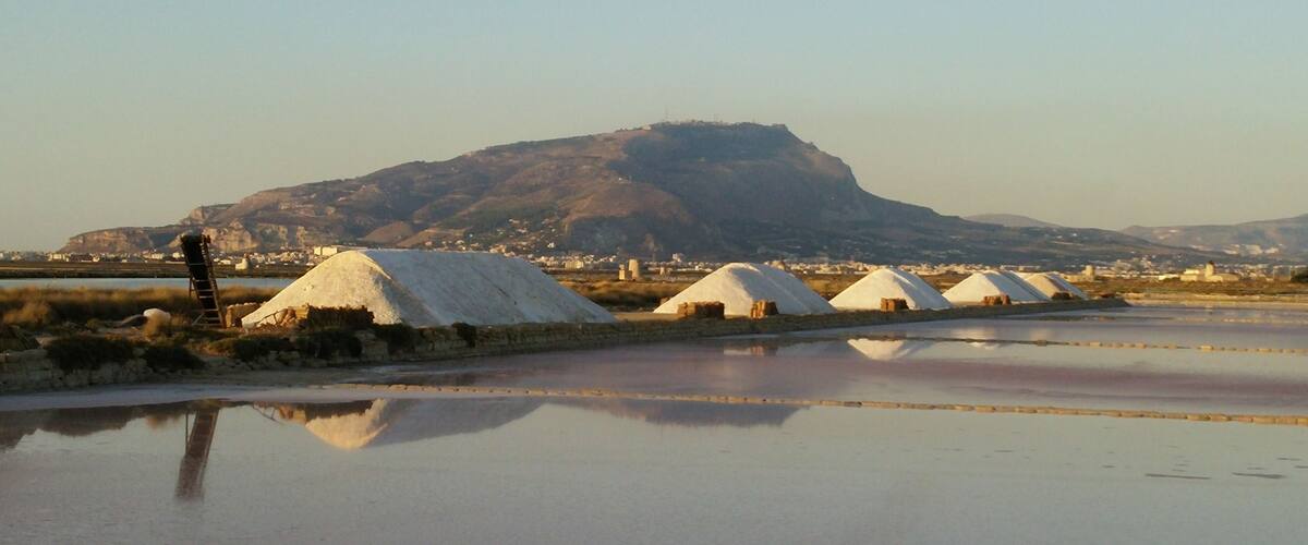 A salt flat with white salt mounds and a mountain in the background.