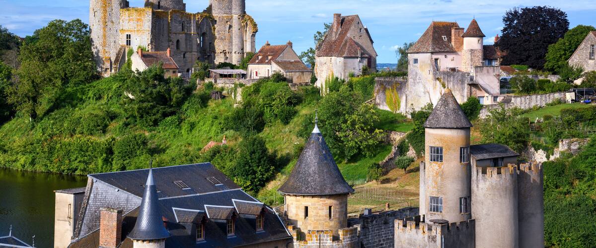 A historic castle with towers and a river in the foreground.