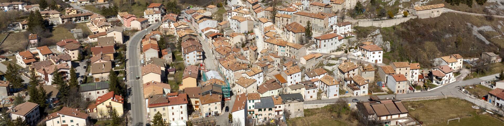 Aerial view of Rocca di Mezzo, a small village on a hill in the province of L'Aquila in Abruzzo, Italy. In the background is the snow-capped Gran Sasso mountain range.