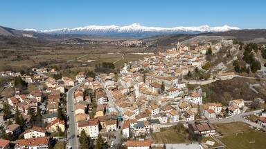 A town with a river, surrounded by mountains and snow-capped peaks.