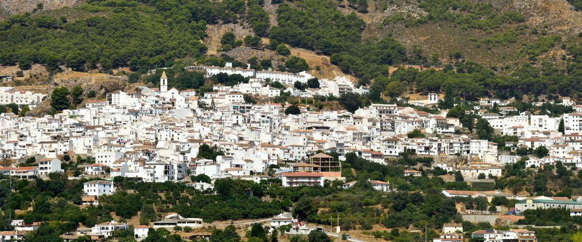 A densely packed hillside town with white buildings and a prominent church tower.