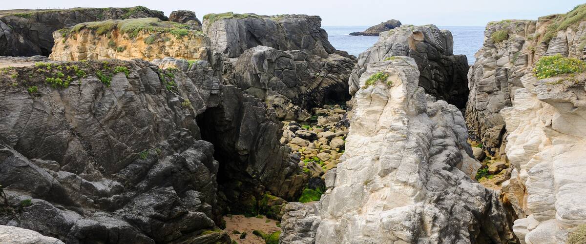 A rocky coastal landscape with cliffs and a narrow passageway.