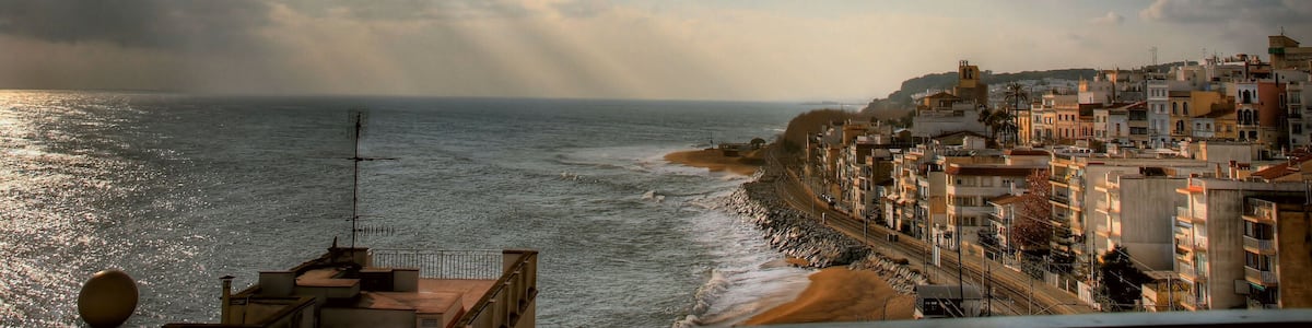 Un paysage urbain côtier avec des bâtiments le long de la côte, une plage et un ciel nuageux.
