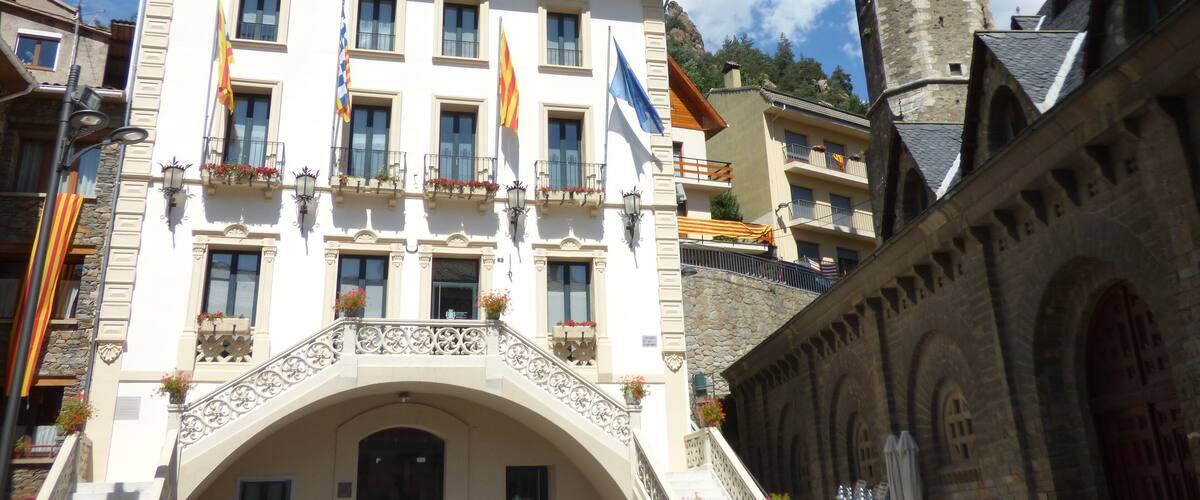 A historic building with multiple flags, a stone tower, and an ornate archway.