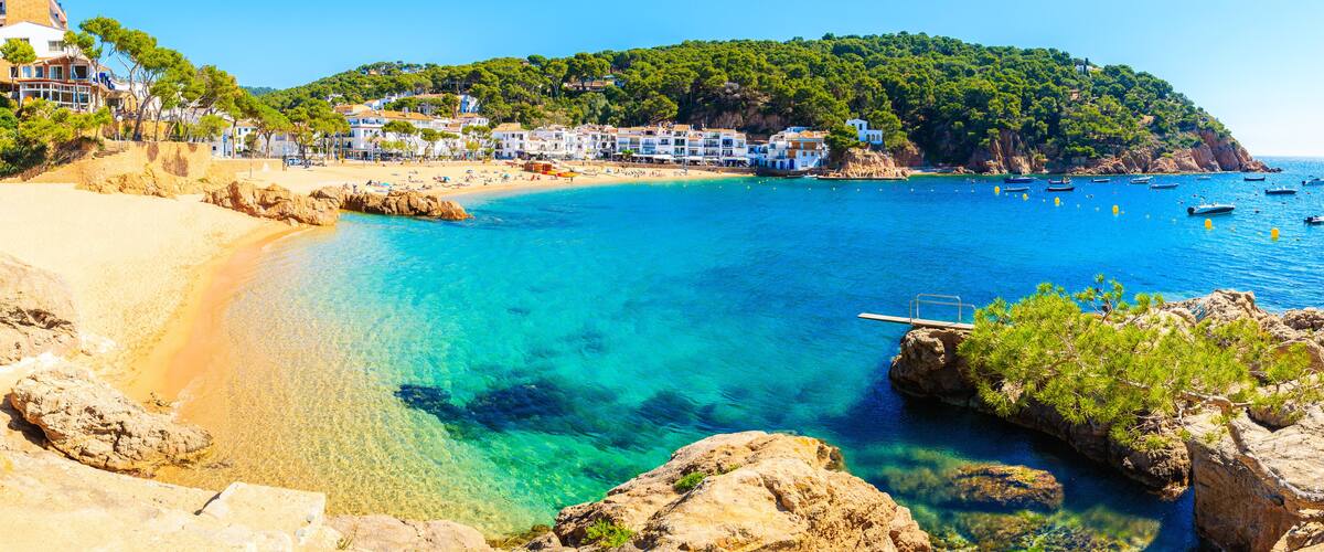 A coastal town with clear turquoise waters, sandy beaches, and a rocky shoreline.