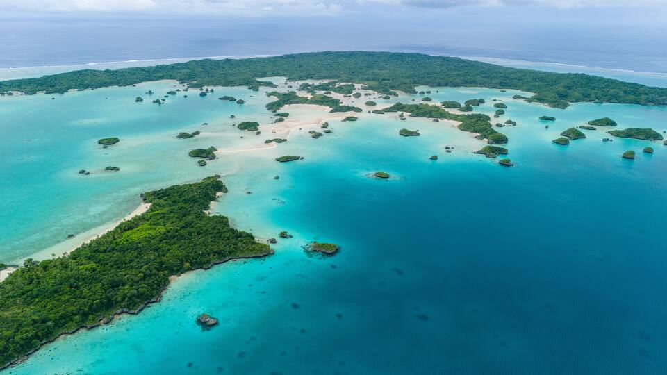 An aerial view of a tropical island archipelago with clear turquoise waters and lush green islands.