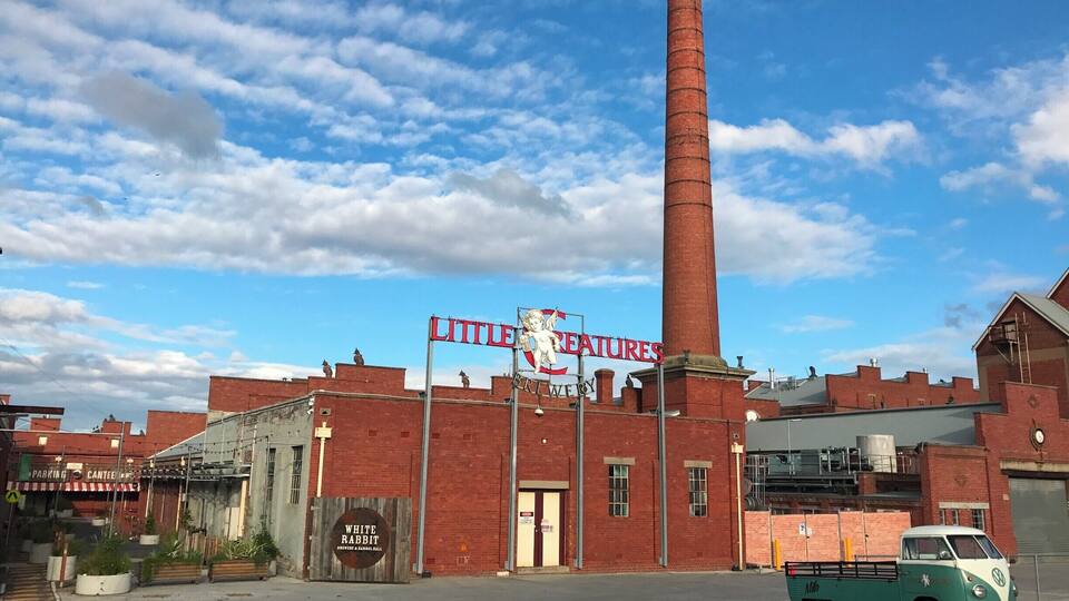 A brick building with a tall chimney, a vintage VW van, and a sign for 'Little Creatures Brewery'.