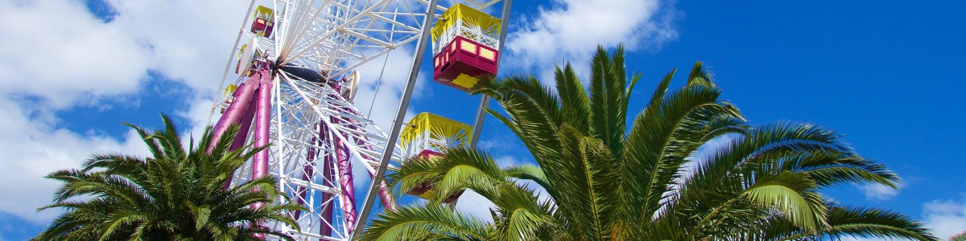 A tall Ferris wheel with colorful cabins against a blue sky.