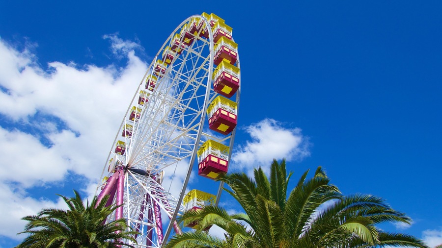 A tall Ferris wheel with colorful cabins against a blue sky.