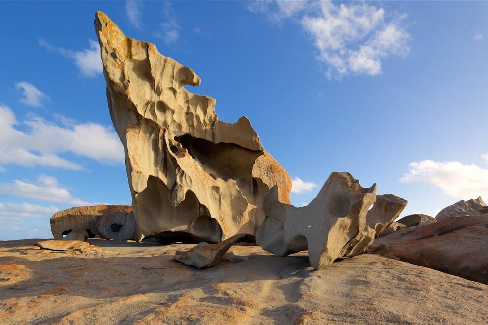 A large rock formation with a prominent overhang against a clear blue sky.
