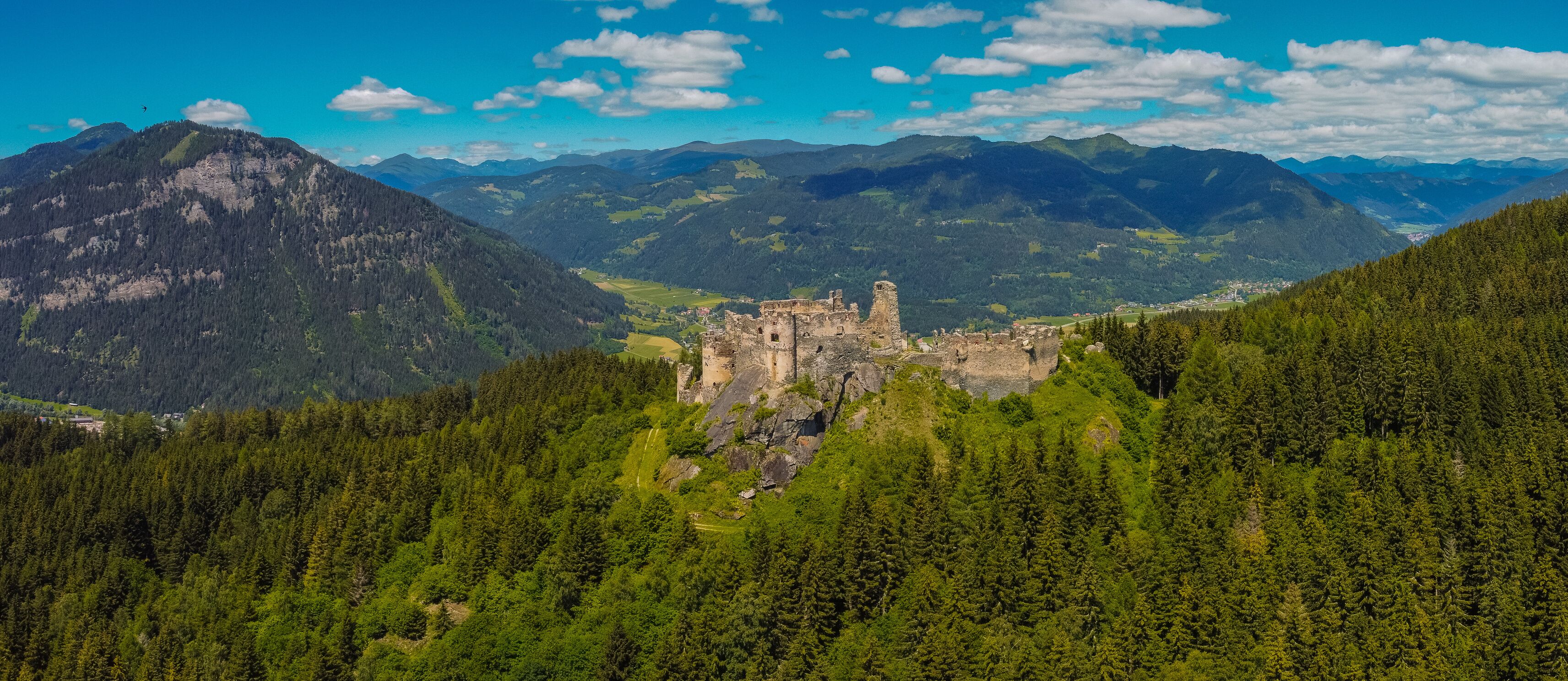 Aerial drone panorama of Steinschloss castle ruins rising above the mura valley in styria, Austria. Medieval ruins in Austria on a sunny day.