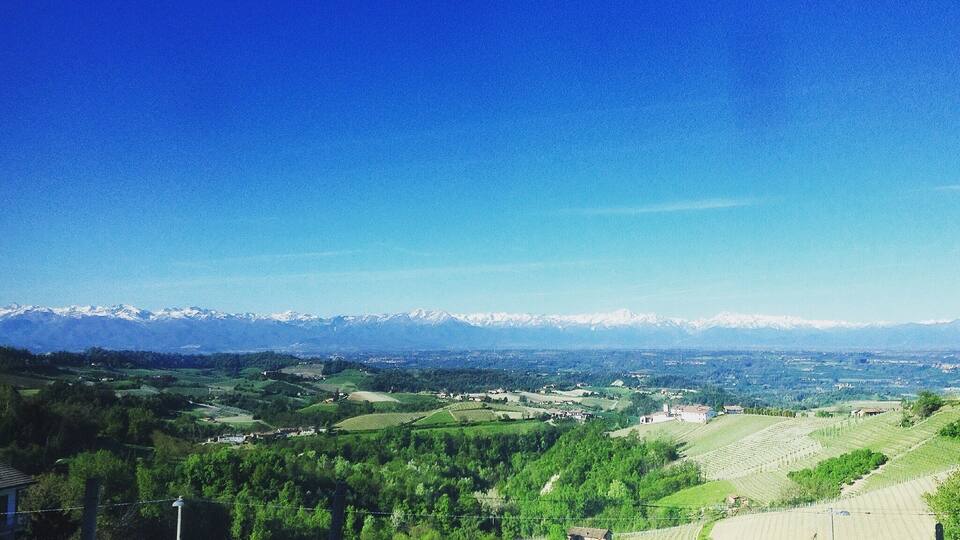 A valley with fields, a small village, and snow-capped mountains in the distance.