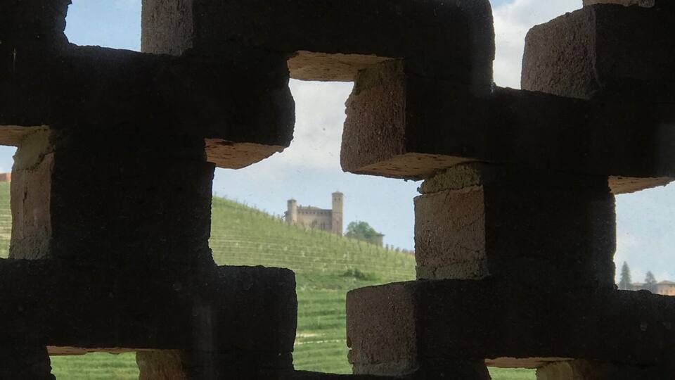 A brick structure with a view of a distant hill and a tower.