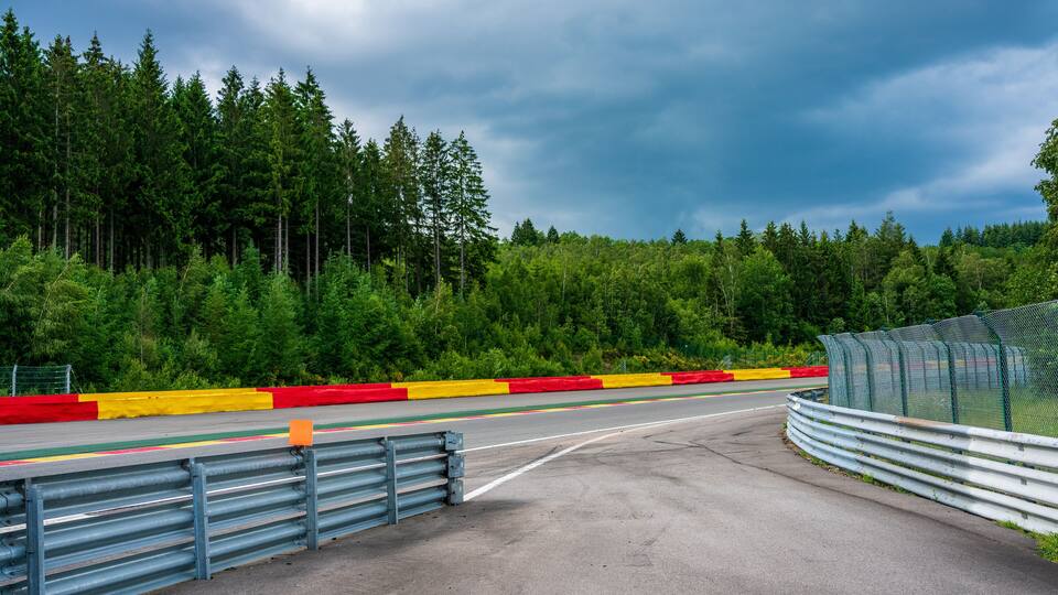 A racetrack with a forested background and a cloudy sky.
