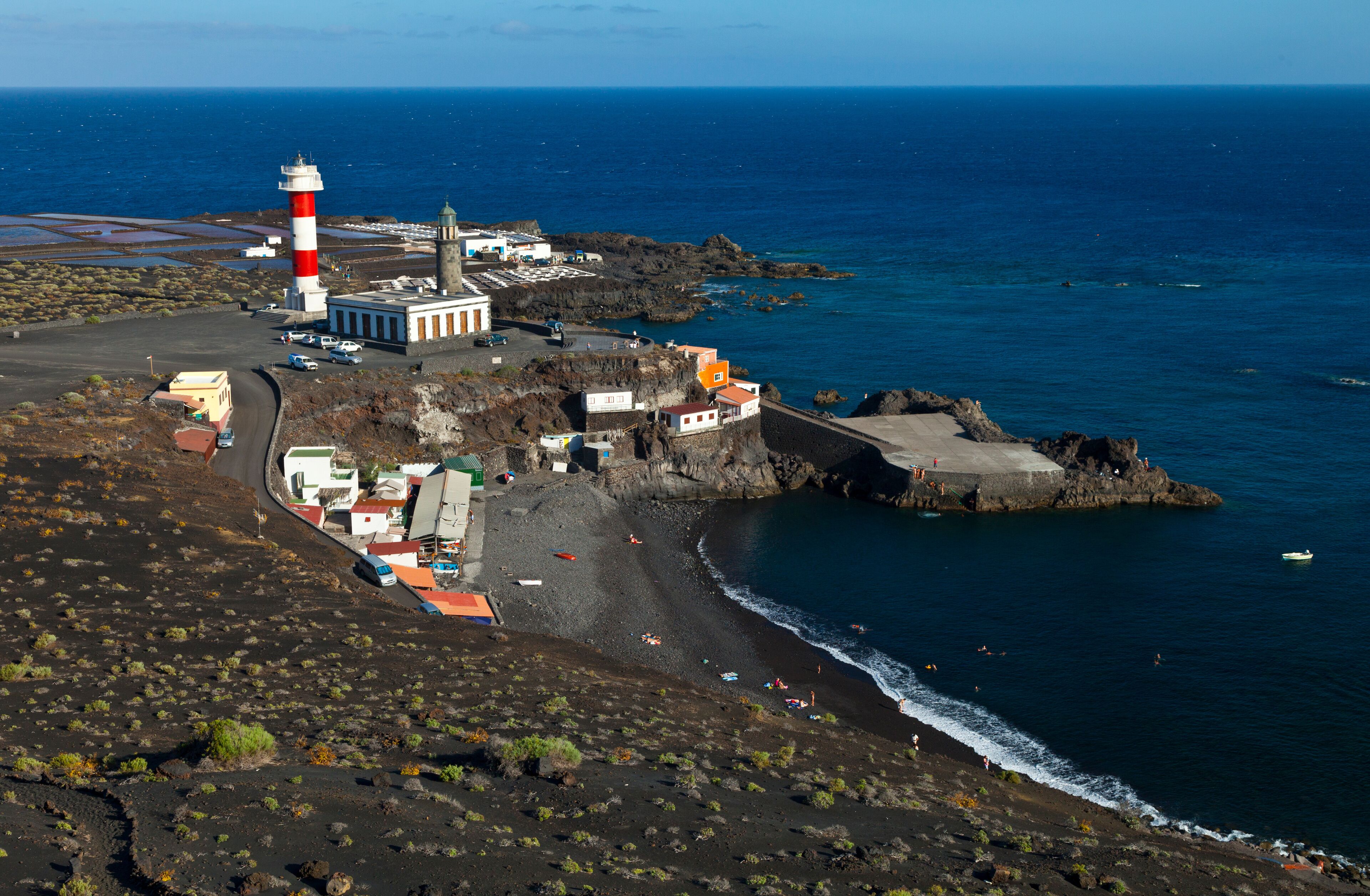 A coastal town with a lighthouse, rocky shoreline, and a beach.