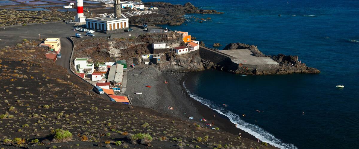 A coastal town with a lighthouse, rocky shoreline, and a beach.